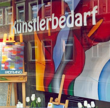 Schaufenster mit Bildern, Staffeleien und der Aufschrift „Künstlerbedarf“.